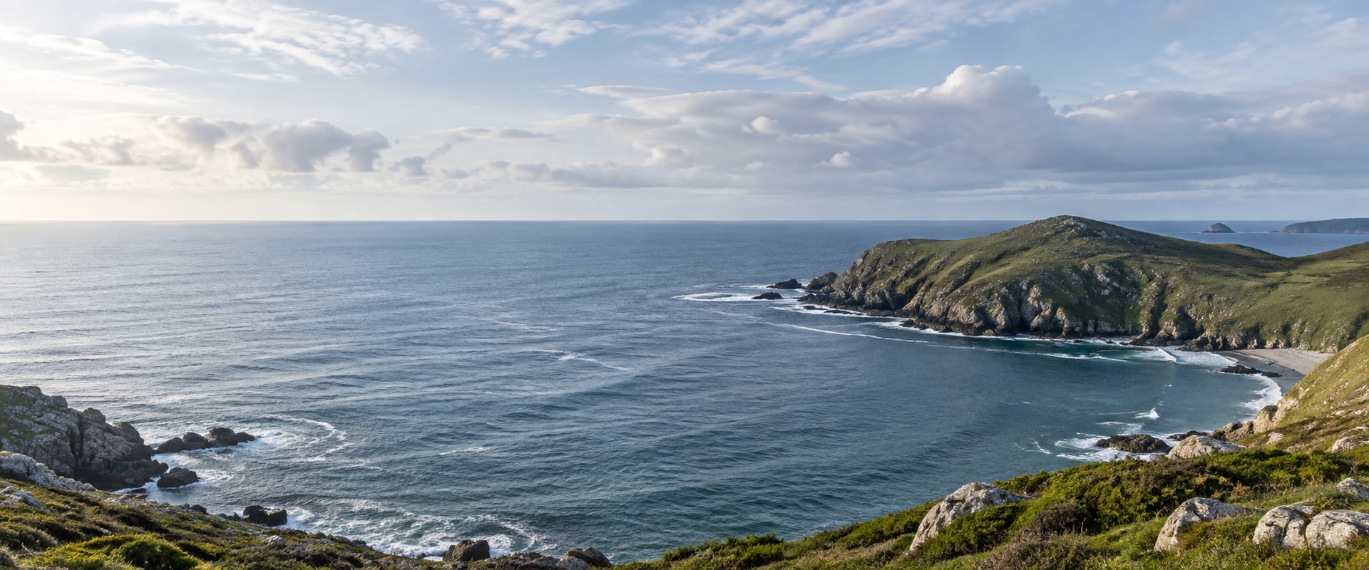 A quiet bay beneath low green coastal headlands.